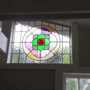 Leadlight stained glass Whangarei. Large circular stained glass window. A rose design with bright reds and greens